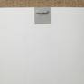 Back view: image of the type of hook that is fixed with double-sided tape to the board for hanging.