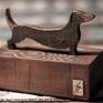 A small tabletop sculpture of a Dachshund created out of steal with a bronze and gold patina mounted on an old growth larch wooden base.