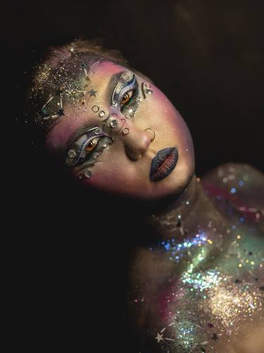 Creative make-up of a girl with rhinestones and piercing thumb