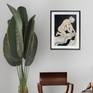 painting in frame on wall next to plant and chair