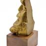 A "broken" head in pressed brass with gold patina, on a wooden base.