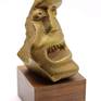 A "broken" head in pressed brass with gold patina, on a wooden base.