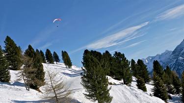 The dome of the parachute slowly flies over the mountains thumb