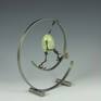 Egg is made from cast polymer resin. limbs are hand fabricated form copper tubes and wires. Articulable joints are made from copper disks with over 100 hand punched holes to capture desired posture, then sealed permanently with fixative. Figures are attached to the steel base with magnets.