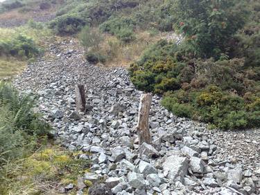 Two upright logs on a stone bed. thumb