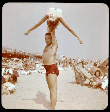 Man holds woman above head at beach thumb