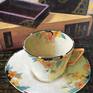 Acrylic rendering of items on a tabletop - art deco cup & saucer, book and cards in wooden box.