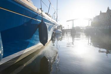 Blue boat docked along the river Spaarne in Haarlem at dawn thumb