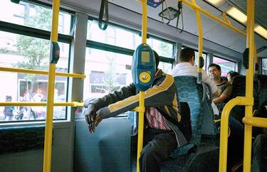 Man in yellow stripped jacket on bus. thumb
