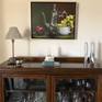 The painting -- framed in a silver floater -- perfectly compliments an antique china cabinet (housing the original teapot).