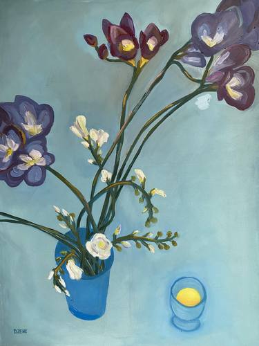 Freesias in a blue vase next to blue glass with fresh orange juice thumb