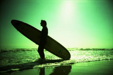 Surfer carrying surfboard in surreal silhouette in green in sea ocean water by beach 35mm analog xpro cross lomo lca photo thumb