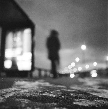 Man waiting at bus stop at night in winter square black and white analogue medium format film Hasselblad photo thumb