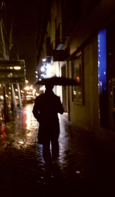 Man walking in street at night in rain color 35mm analogue photojournalism portrait photograph thumb