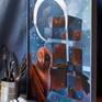 The artwork framed on the worktable, with paint and brushes nearby to indicate scale.