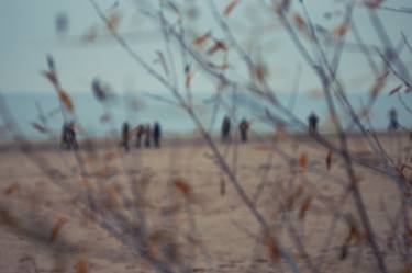People walk on autumn beach through the branches of the bushes thumb