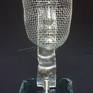 The sculpture was created after melting the strip of glass on a steel mesh (face). The sculpture is fastened with a steel holder to the glass base (self-assembly).