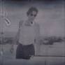 Leaving II (Sidewinder) - 2005

60x110cm, Edition of 10.
Digital C-Print based on a Polaroid.
Signature label and Certificate.
Artist Inventory No. 3436. 
Not mounted. 

2005  SIDEWINDER - Director / Artist  / Camera / Editing - starring JD Rudometkin, Stefanie Schneider, music by JD Rudometkin

private history turned into an intimate mythology of elemental fantasies where reality is perceived through a veil of psychedelic memories and unconscious projections. such is a collection of passions and dreams, an uncanny diary of ephemeral narratives and mental intensities in Stefanie Schneider’s painterly photographs where subjectivity of an ontological doubt uses a poetics of pastische as a vehicle for an intertextual journey towards the truth and the authenticity of primary emotions. here time is immersed in a nostalgic suspense of oneiric dimension, a sort of ambiguous coma of silence and comfort, and open space embraces a psychotic landscape of solitude and accidental pleasure. fetishisized surface of extreme feelings gives a stage for an unsolicited promise of unconditional love and unlimited freedom, a promise framed by sensual tension between fulfillment and expectation. (Adam Budak, Kunsthaus Graz, Oct 2005)

Sidewinder
There’s blood on the dress that hangs in the Airstream trailer outside 29 palms. With the pistol in her sweat palm touching at his temple. Tell me what god’s gonna do for me and you now Stevie’s saying while Brother John Baptiste looks there across to where her cat seems weak and fed. All the good that comes to me from my believing man, I wanna hear about it said to me like that. Just the way you breathed it like you did 10 minutes ago when I was wrapped so well around your head. Silence then. A baby screams his mother out in the dessert night who wakes so late. Orion is a belt John Baptiste looks at through the torn-screen trailer window. There, touching his calf are vipers crawling now across her feet between his knees in front of her he kneeling for his life and they are full of venom with their broken fangs.

A gun at head, where even his breath, so short, is preaching. He’s in a wheat field. John Baptiste. Counting birds on telephone wires hung low in afternoon where his mother’s call cannot now reach him. There she stands a weeping willow with the sidewinder underneath the trailer step a drop of blood upon her ankle with the bullet through its head. A scar follows sweat palm to wrist. Torn Stevie. Scars from the weapon to her toes an accidental act of God her father said. On Vaness at California 16 years ago but who’s counting 6 bullets for the barrel wait beside the temple. The long white shaft of tissue hemmed together gods tattoo along her ribs, hip to breast. She wants to fuck the preacher in her trailer with his bible on the alter front row Stevie asks forgiveness holy father from the car that shook her bones apart. John Baptiste asks to pray before she leads his temple head.

For twenty minutes darkness hides the accidents in trailer shade her childish screams a preacher underneath her shimmer blue bled dress. The prayers he said beside the bed with mother for relatives with tumors, brand new bicycles, and rain. Stevie takes the whisky in her mouth to wash him out the sidewinder skids across her wounded foot of scars. John Baptiste asks the Lord to heal her in the new day that is breaking mouth of whisky spits it laughing father forgive the trigger finger for the viper he gives thanks.

And takes the barrel toward his lips through mumbling supplication kiss it Brother Stevie offers, please, but doesn’t wait him there. Copper penny Sunday School upon the tongue. And closed his eyes. A blur of her and mother. Other bodies. Women, gently crushing spirits. Prayers. His han under her weight in grams. The fingernail fang and fucks it. So slid the pull of metal out As god can answer. And into her mouth then. Settles. And wet the metal. He touches her, his finger. Viper like. And fuck it sore. Believers. Repentant whore forgiven preacher leaving town in that old ragtop down and left a rag dress bleeding in the Airstream soft, again. (JD Rudometkin)

“Working on Sidewinder with Stefanie Schneider was intense. It is a very personal piece for both of us, though I feel in very different ways. When overdue fears and aspirations are able to surface in a project, the work becomes a mirror. Such efforts are always a risk. I am still uncertain of what exactly to make of it Sidewinder. How much should have been exposed. What needs to remain sacred. I almost did not drive that „68 Deville” out to 29 Palms on the day we were set to shoot. I followed her out there against a feeling I had. Was it fear? I don’t know. Perhaps mistakes do not exist. What is our intuition composed of anyhow? When I look out across the desert, it seems so flat. So free of dramatic lines. That is when a human figure appears, even in the distance, a curiosity. There are so many of us clustered in these cities, who would care. Why take the time? I will always drive out of town back into parts of Sidewinder from time to time.”(JD Rudometkin)

------

In the case of Sidewinder the scenario was created by internet where she met J.D. Rudometkin, an ex-theologian, who agreed to her idea to live with her for five weeks in the scrubland desert
environment of Southern California. The dynamics and unfolding of their relationship, both sexually and emotionally, became the primary subject matter of this series of photographs. The relative isolation and their close proximity, the interactive tensions, conflicts and submissions, are thus recorded to reveal the day-to-day evolution of their relationship. That a time limit was set on this relation-based experiment was not the least important aspect of the project. The text and music accompanying the DVD were written by the American Rudometkin, who speaks poetically of “Torn Stevie. Scars from the weapon to her toes an accidental act of God her father said. On Vaness at California.” The mix of hip reverie and fantasy-based language of his text, echoes the chaotic unfolding of their daily life in this period, and is evident in the almost sun-bleached Polaroid images like Whiskey Dance, where the two abandon themselves to the frenetic circumstances of the moment. Thus Sidewinder, a euphemism for both a missile and a rattlesnake, hints at the libidinal and emotional dangers that were risked by Schneider and Rudometkin. Perhaps, more than any other of her photo-novels it was the most spontaneous and immediate, since Schneider’s direct participation mitigated against and narrowed down the space between her life and the art work. The explicit and direct character of their relationship at this time, opens up the question as to the biographical role Schneider plays in all her work. She both makes and directs the work while simultaneously dwelling within the artistic processes as they unfold. Hence she is both author and character, conceiving the frame within which things will take place, and yet still subject to the same unpredictable outcomes that emerge in the process.

(Mark Gisbourne, Stranger than Paradise, 2006, page 12-14)
