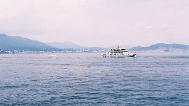a japanese ferry on the water against a mountainous backdrop thumb