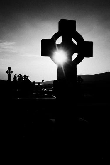sun setting through celtic cross ireland thumb
