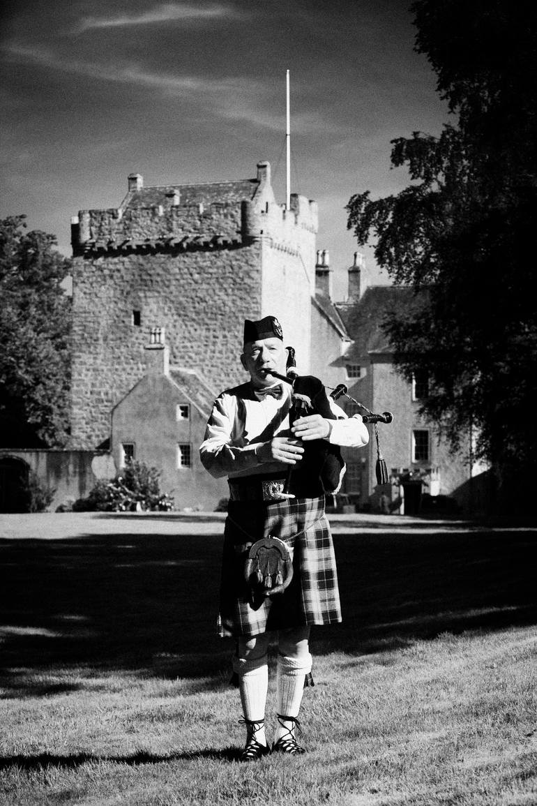 scottish bagpipe player playing pipes in front of kilravock castle