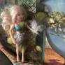 A bird has disappeared from a vintage aviary print...signaling a change in the world order. This assemblage features a miniature figure, resting on a branch, wardrobed in feathers and bejeweled with Swarovski crystals. A crystalized bloom is prominent in the foreground, along with dried nature plants. this piece is framed in a white wooden frame. Also see Modern Aviary #2 for a wonderful set!