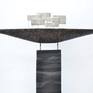 Black ship with sails on a black, white and grey  column. The ceramic ship and the column are coated with layers of colored slips, glaze and ceramic pigments, thus creating an alternating glossy or matt surface.