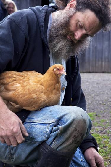 Farmer with chicken resting on leg. thumb