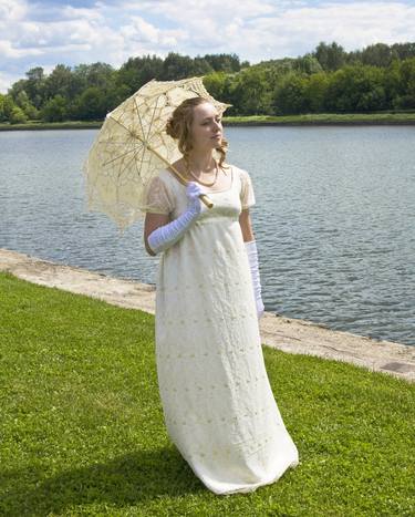 Woman in white historical dress of 19 century on bank of river thumb