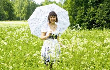Beautiful woman with white umbrella on meadow in blossom thumb