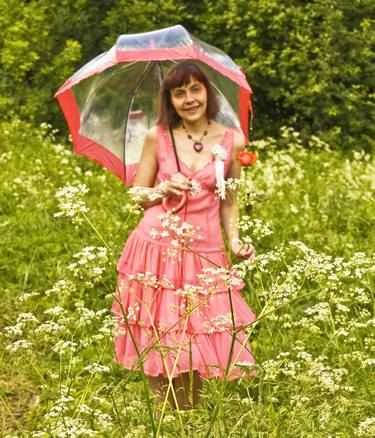 Beautiful woman in pink with umbrella on meadow in blossom thumb