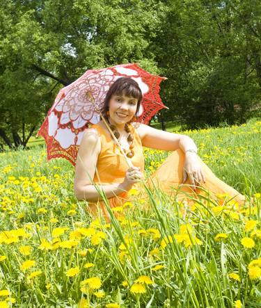 Beautiful woman with umbrella on meadow with yellow dandelions thumb