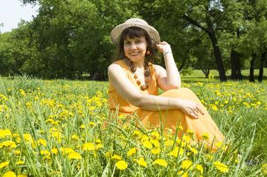 Woman in hat on meadow with yellow dandelions thumb