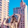 From a limited edition of 5 archival photographs
Signed and numbered by artist A K Nicholas

Blush pink verticals dominate this image in three scales: the buildings, the model’s legs, and her high heeled shoes. The blue negative space of the sky pierces downward in pencil thin slivers between the buildings.