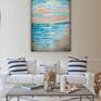 A highly textured painting with palette knife and brush giving an impressionistic expression of shoreline. There are surfers in the distance waiting for a wave.