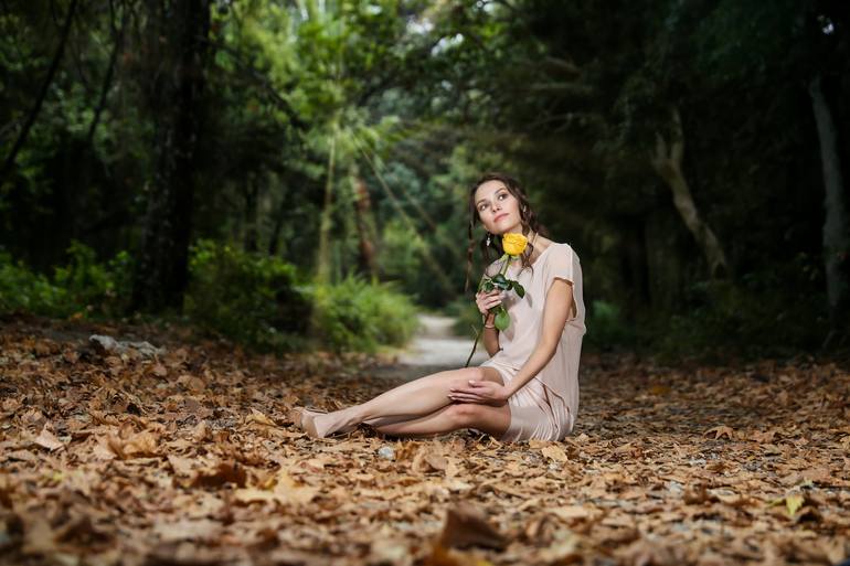 A young woman sitting in the forest and holding a yellow rose - Print