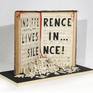 "Indifference lives in...silence!" is carved on an old music sheet. The single letter fallen in front of the book.