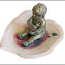 A sculpture made in away to express emottions through anarrative.an infand holding his milk in a shellwhere he feels safe though danger has already been in a short distance.glazed ceramic and acrylic paint used to show a childs figure,like a pearl in a shell damaged by the consequences of war