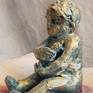 A sculpture made in away to express emottions through anarrative.an infand holding his milk in a shellwhere he feels safe though danger has already been in a short distance.glazed ceramic and acrylic paint used to show a childs figure,like a pearl in a shell damaged by the consequences of war
