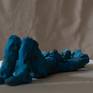 We are on the beach, a woman is  lazily lying down under the blue sun.
The sculpture is made out of clay with blue, mat patinas