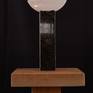 This "lamp-like" abstract sculpture of highly polished stone on stone sits on a small wooden base.